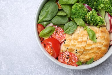 Photo of Healthy meal. Delicious chicken, vegetables and spinach in bowl on light grey table, top view. Space for text