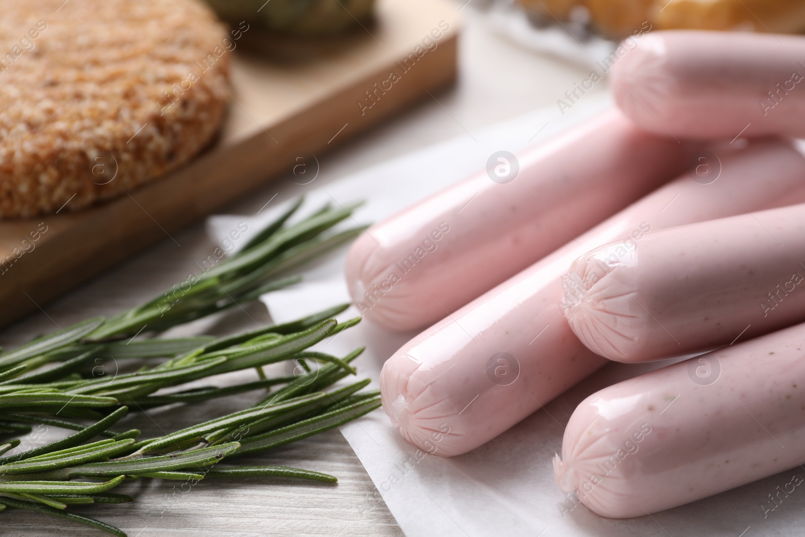 Photo of Vegan sausages and rosemary on white table, closeup