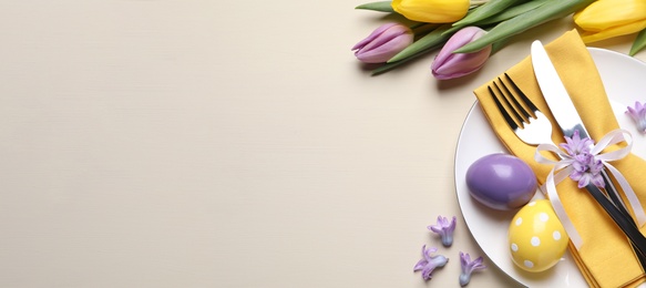 Festive Easter table setting with eggs on beige background, flat lay. Space for text