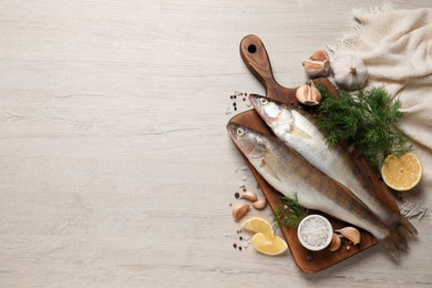 Photo of Fresh raw pike perches and ingredients on light wooden table, flat lay with space for text. River fish