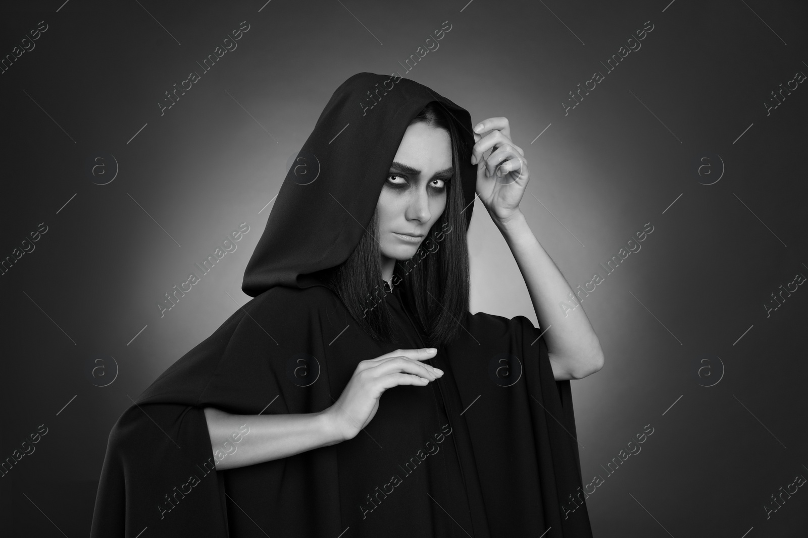 Photo of Mysterious witch with spooky eyes on dark background. Black and white effect