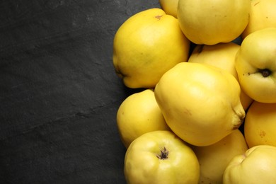 Photo of Fresh ripe organic quinces on black table, closeup. Space for text