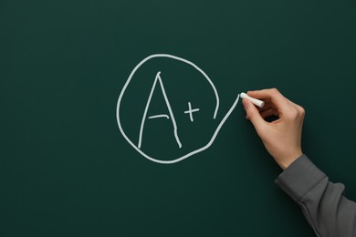 Image of School grade. Teacher encircling letter A and plus symbol with chalk on green chalkboard