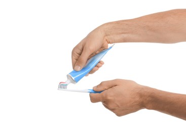 Man applying toothpaste on brush against white background, closeup