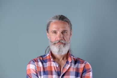 Photo of Handsome bearded mature man on color background