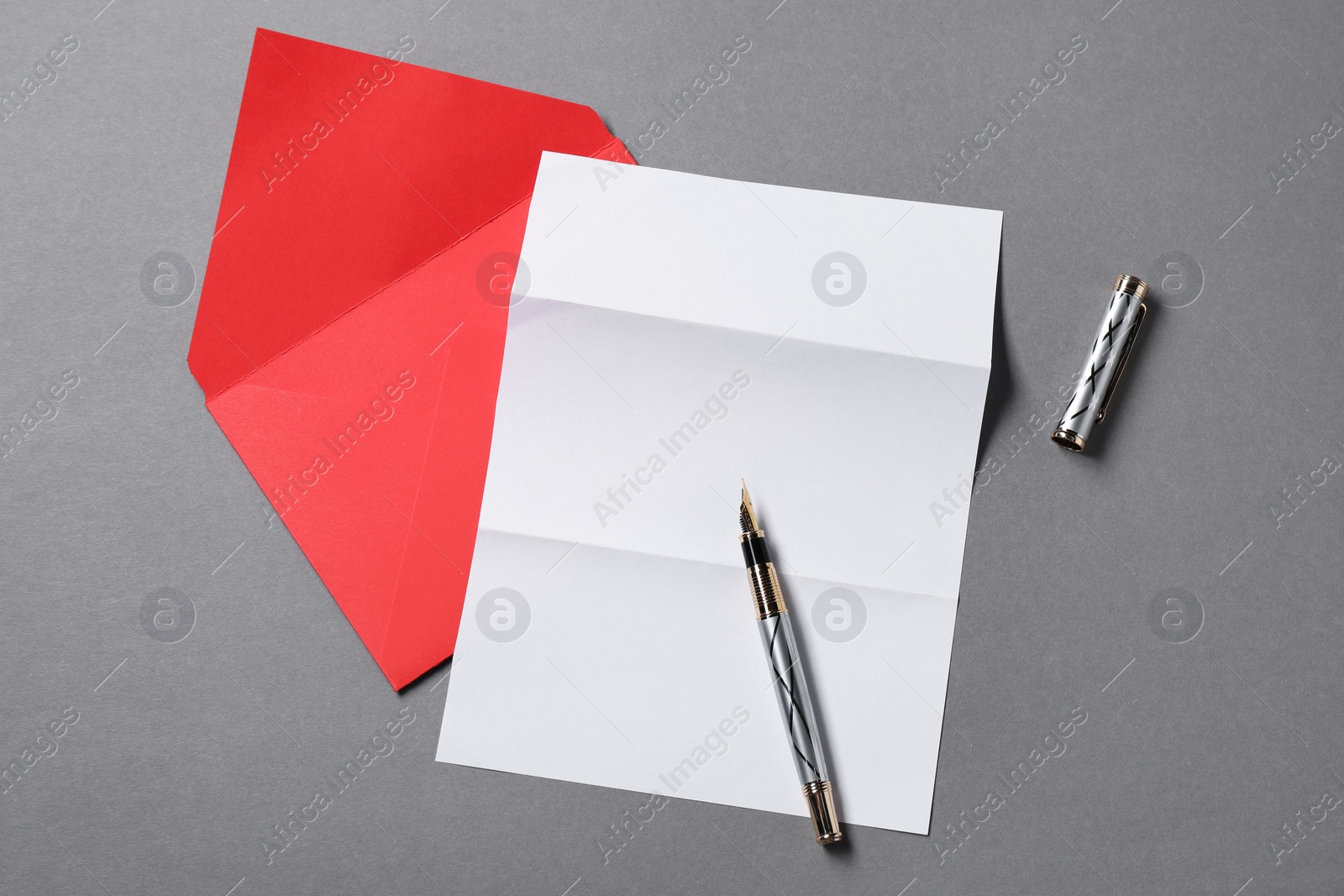 Photo of Blank sheet of paper, letter envelope and pen on grey background, top view