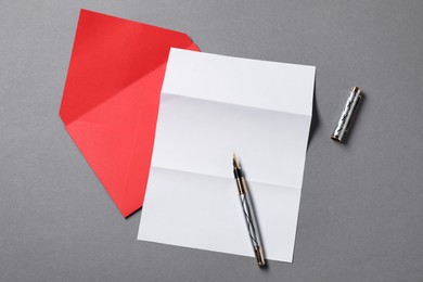 Photo of Blank sheet of paper, letter envelope and pen on grey background, top view