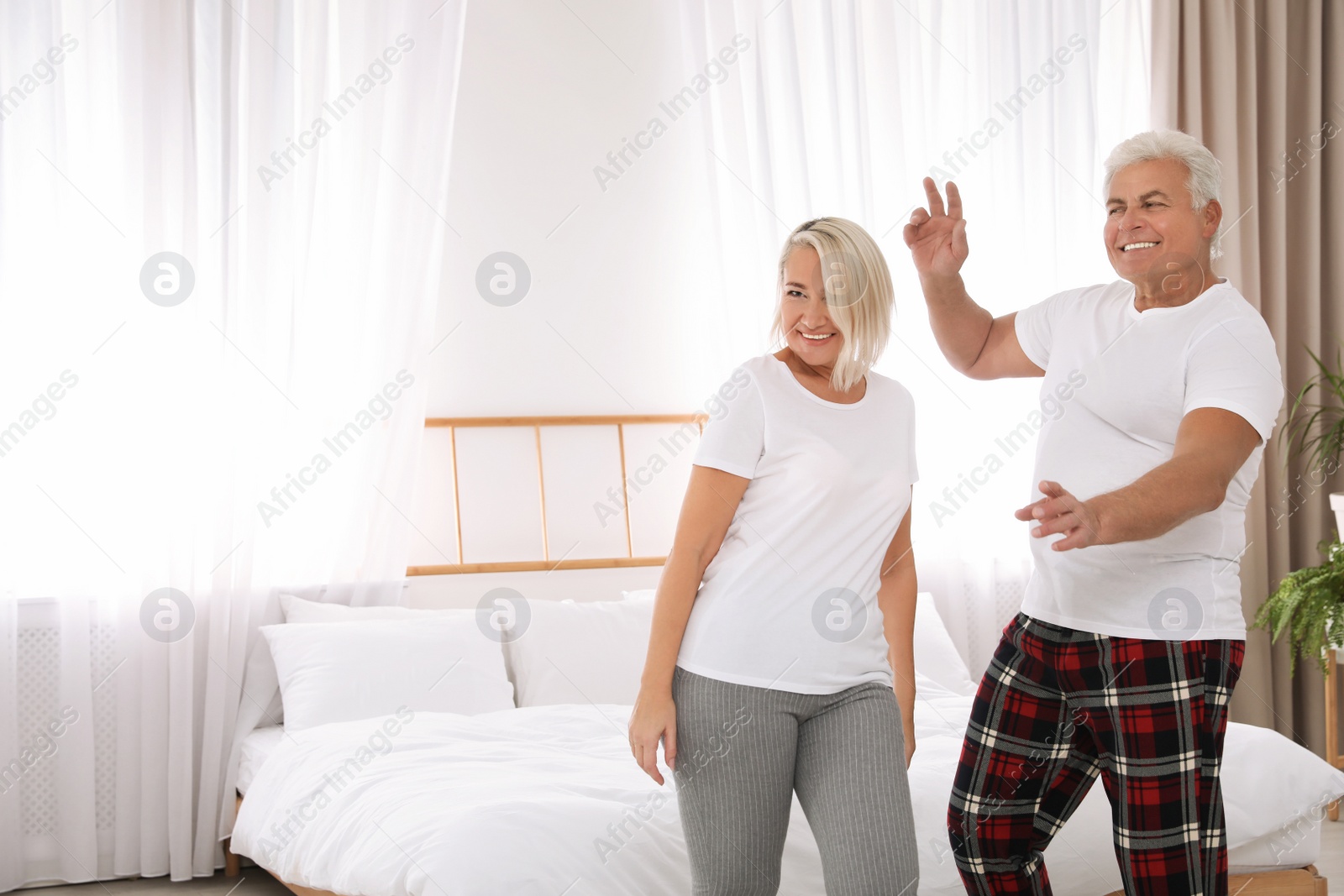 Photo of Happy mature couple dancing together in bedroom