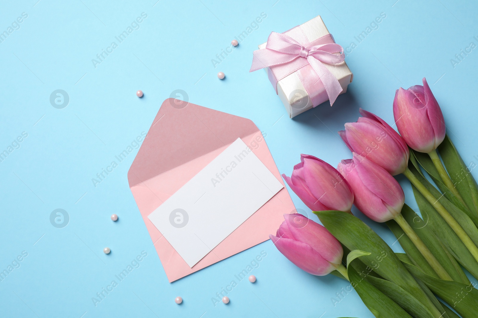 Photo of Flat lay composition with greeting card on light blue background, space for text. Happy Mother's Day