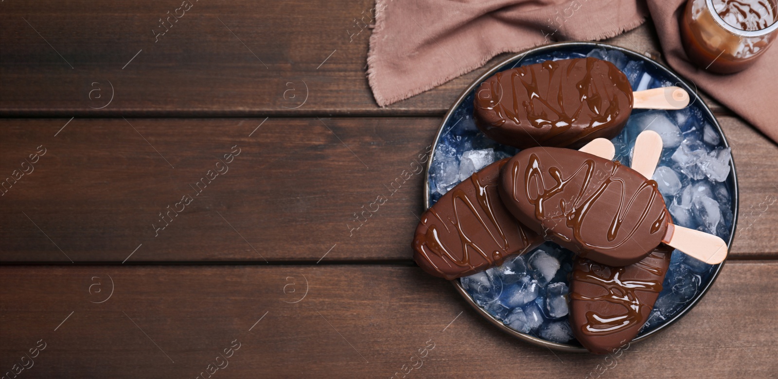 Image of Delicious glazed ice cream bars and ice cubes on wooden table, flat lay with space for text. Banner design