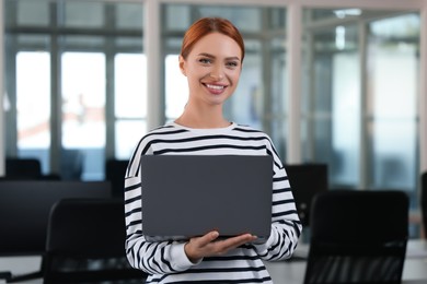 Beautiful happy woman with laptop in office