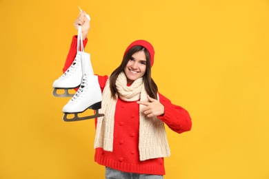 Photo of Happy woman with ice skates on yellow background