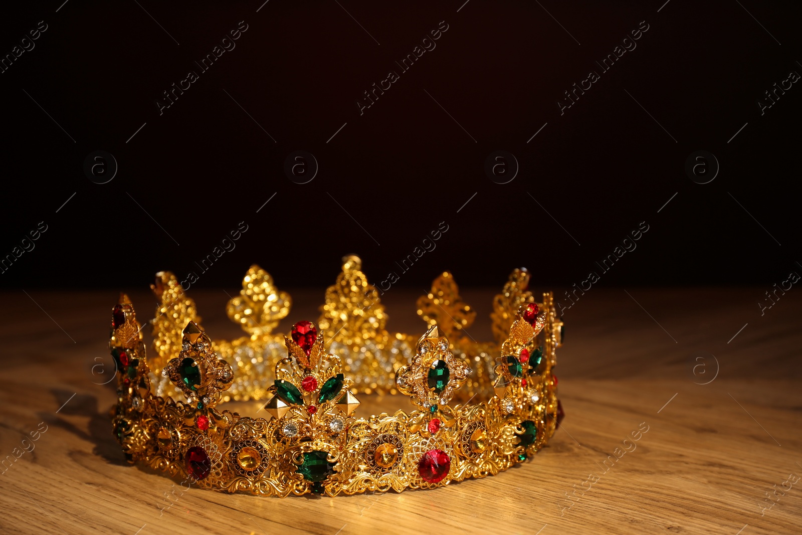 Photo of Beautiful golden crown with gems on wooden table. Fantasy item