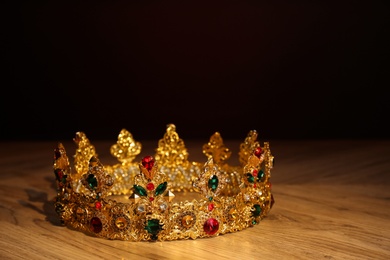 Beautiful golden crown with gems on wooden table. Fantasy item