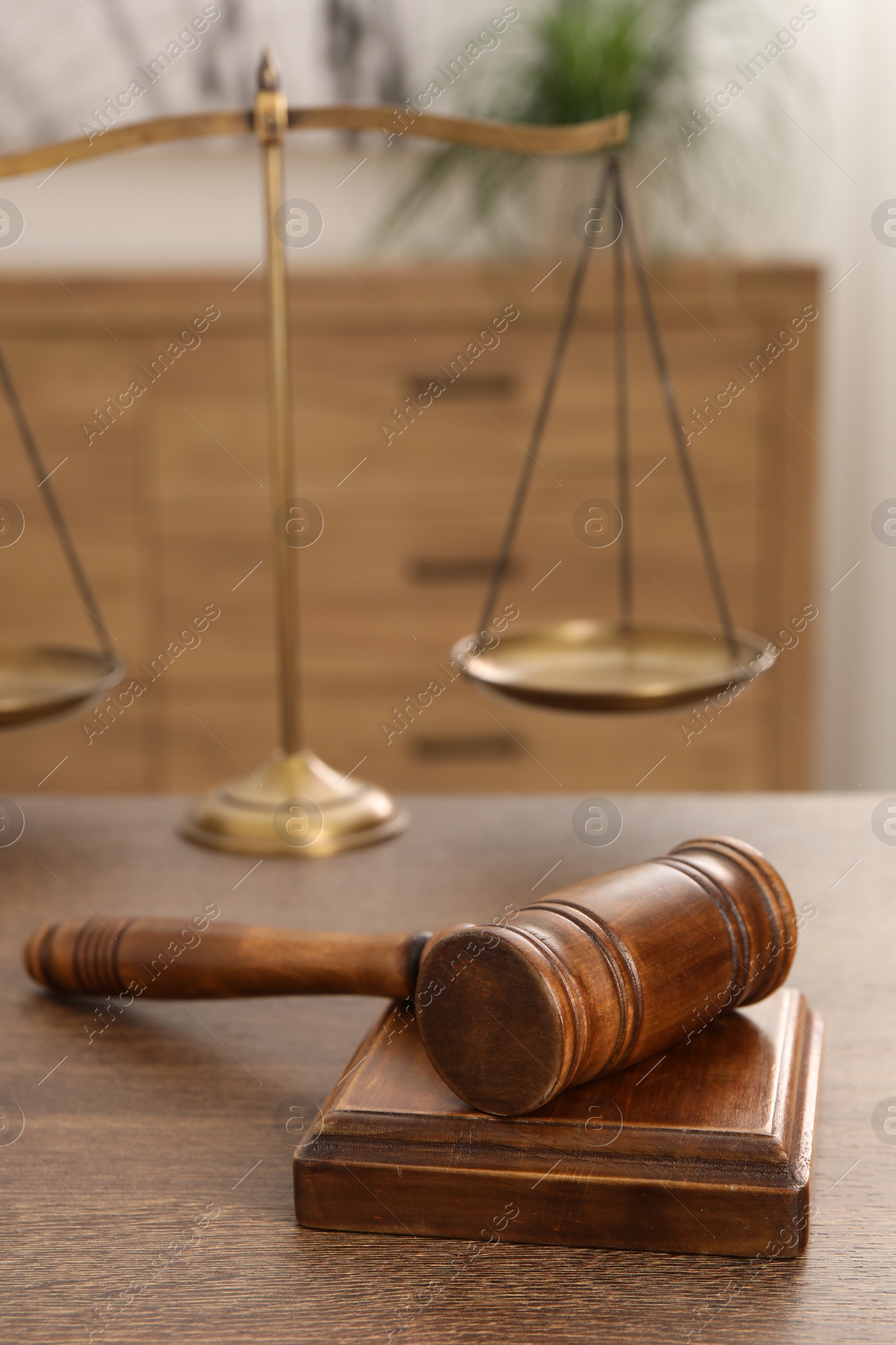 Photo of Wooden gavel, sound block and scales on table indoors