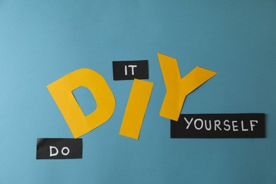 Photo of Phrase Do It Yourself and abbreviation DIY made of letters on light blue background, flat lay