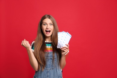 Photo of Portrait of emotional young woman with lottery tickets on red background