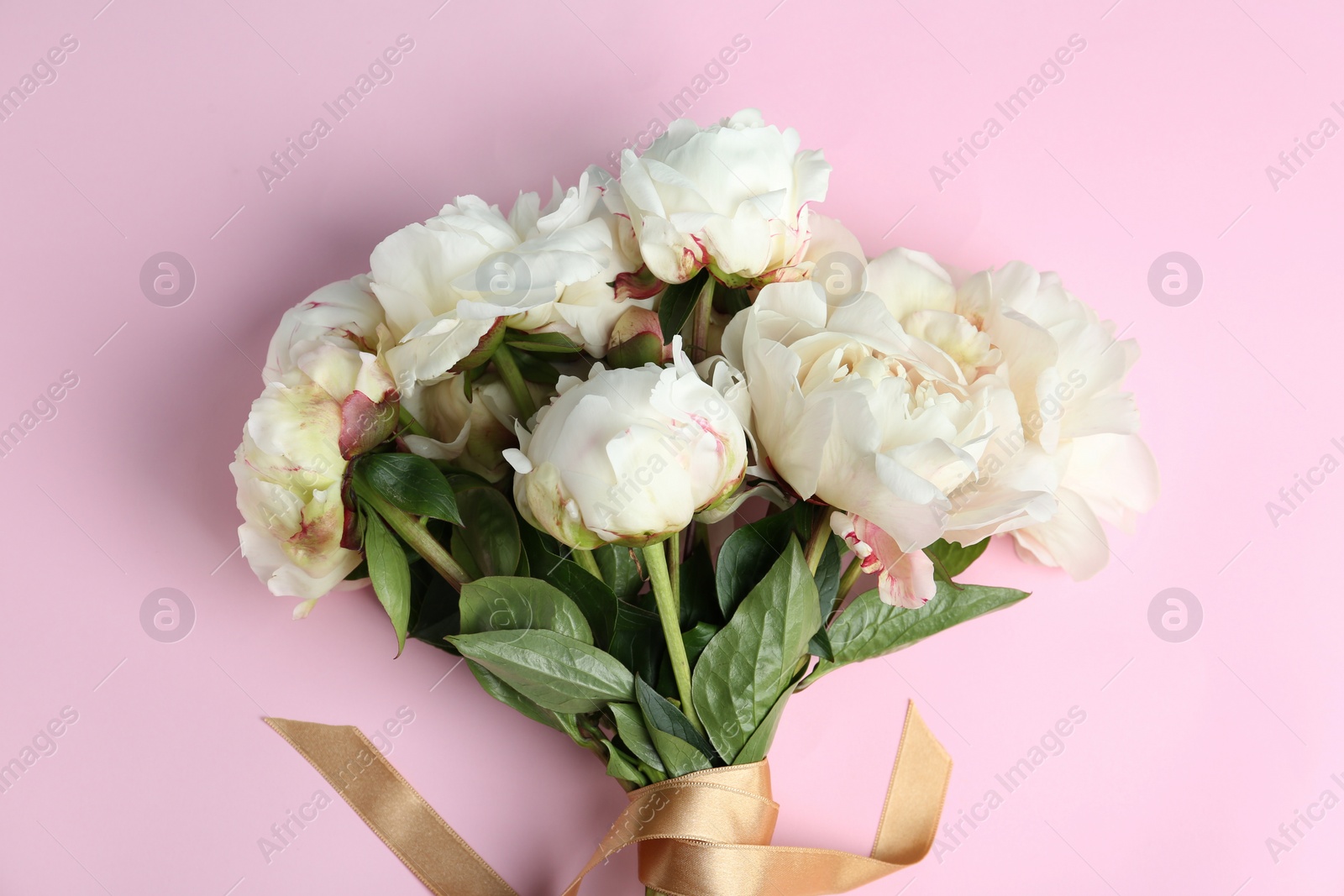 Photo of Bouquet of beautiful peonies with ribbon on pink background, flat lay