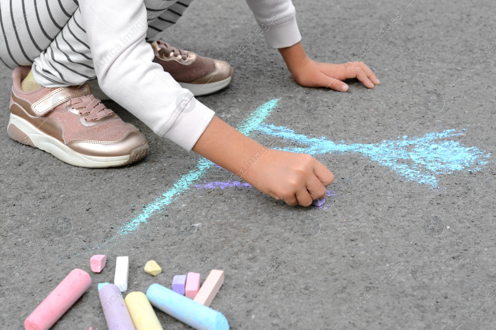 Photo of Little child drawing happy family with chalk on asphalt, closeup