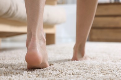 Photo of Woman walking on soft light brown carpet at home, closeup