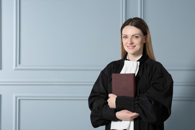 Portrait of smiling judge with book near grey wall. Space for text
