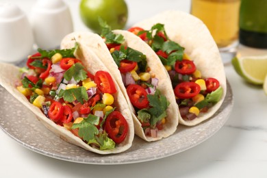 Photo of Tasty tacos with vegetables on white marble table, closeup