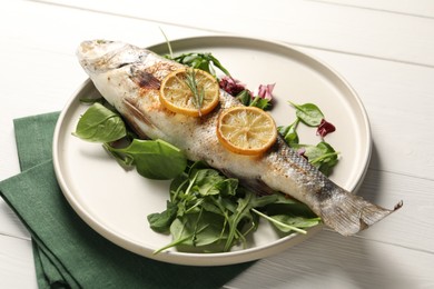 Photo of Baked fish with spinach and lemon on white wooden table, closeup