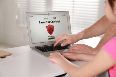 Father installing parental control app on laptop to ensure his child's safety at home, closeup