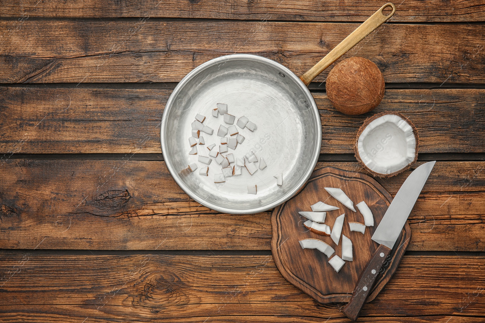 Photo of Frying pan with coconut pieces on wooden background