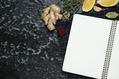 Photo of Blank recipe book and different ingredients on black textured table, flat lay. Space for text
