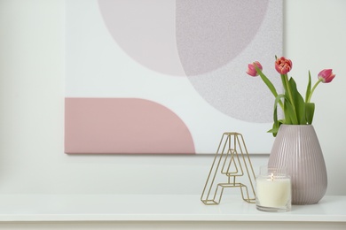Photo of Vase with beautiful tulips, burning candle and decorative letter on table indoors, space for text. Interior elements