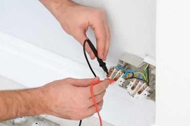 Image of Electrician with tester checking voltage indoors, closeup