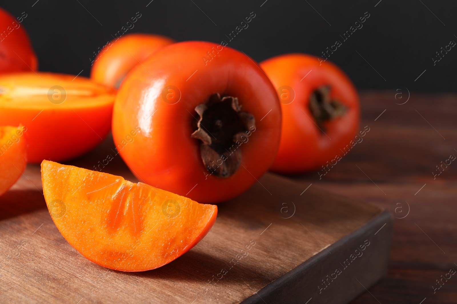 Photo of Delicious ripe persimmons on wooden table, closeup