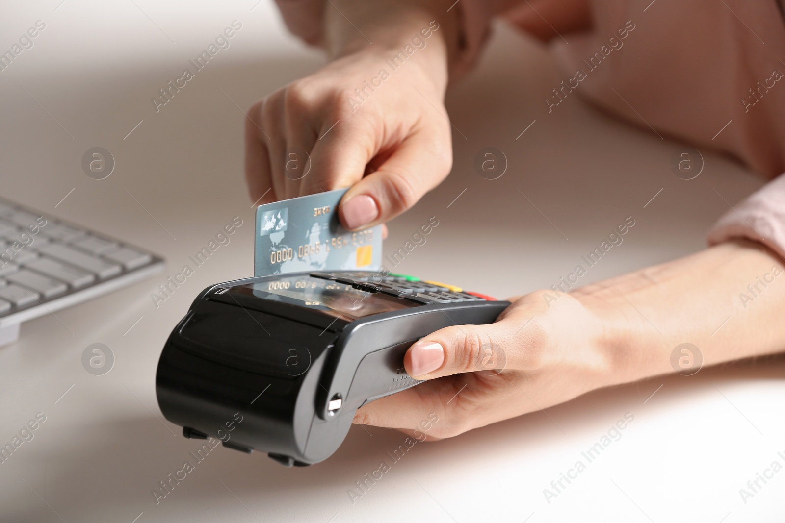 Photo of Woman using modern payment terminal at table indoors, closeup