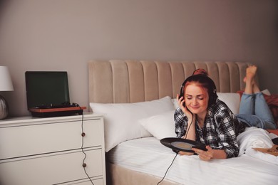 Image of Young woman listening to music with turntable in bedroom