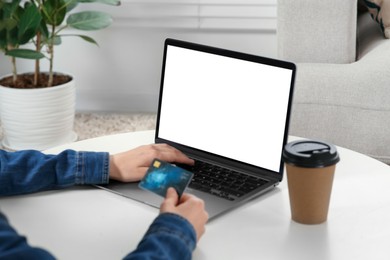 Photo of Woman with credit card using laptop at white table indoors, closeup