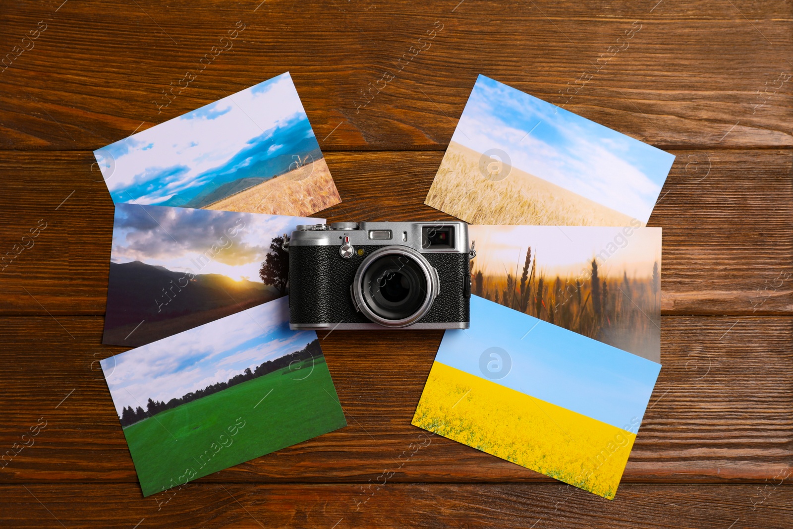 Photo of Vintage photo camera and beautiful printed pictures on wooden table, flat lay. Creative hobby