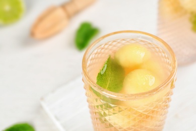 Photo of Glass with tasty melon ball drink on table, closeup