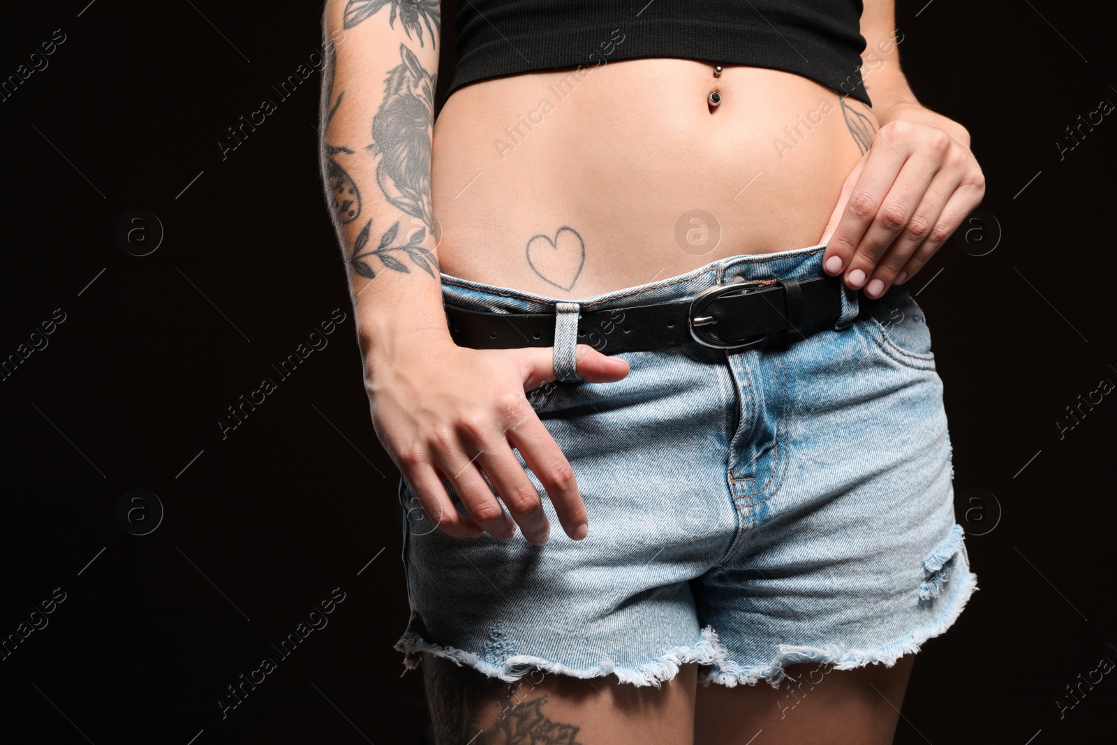 Photo of Woman with tattoos on body against black background, closeup