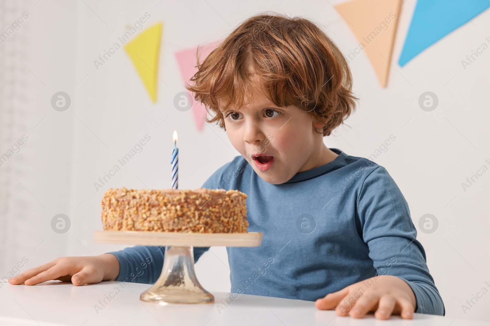 Photo of Cute boy with birthday cake at white table indoors