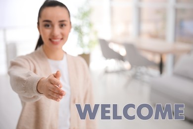 Happy young woman offering handshake indoors, focus on hand. Welcome to team