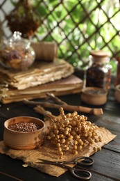 Photo of Flax seeds with dry flowers and scissors on black wooden table indoors