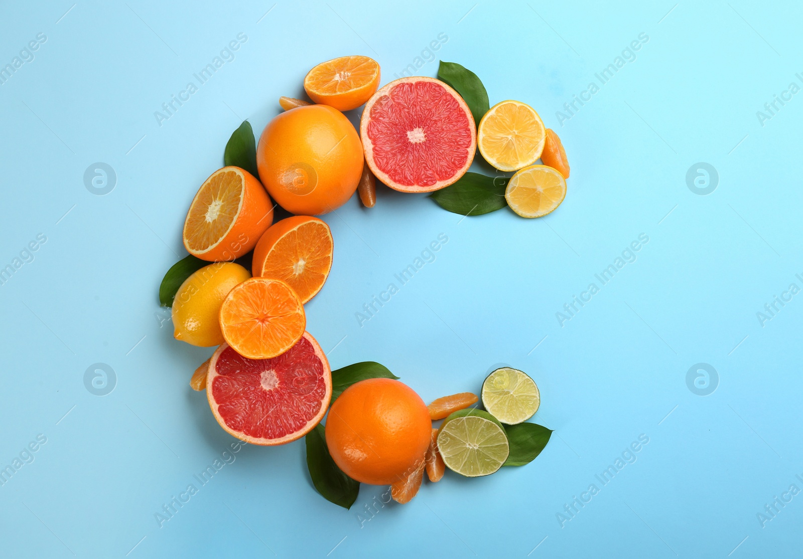 Photo of Letter C made with citrus fruits on light blue background as vitamin representation, flat lay