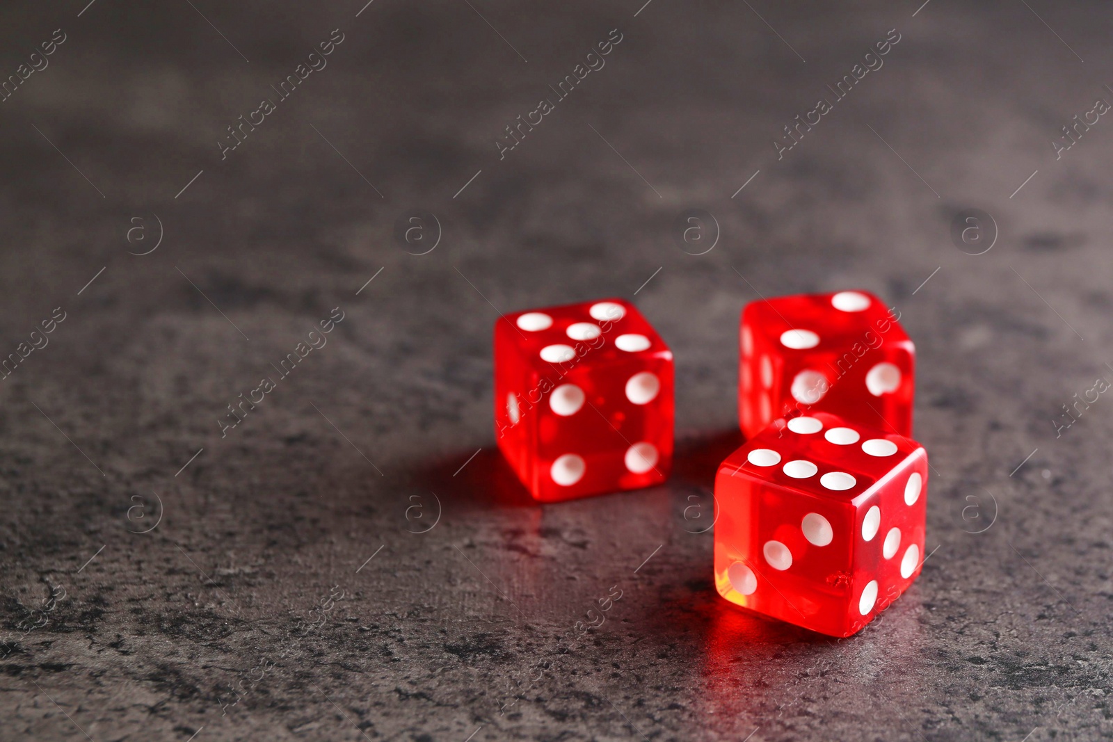 Photo of Three red game dices on grey textured table