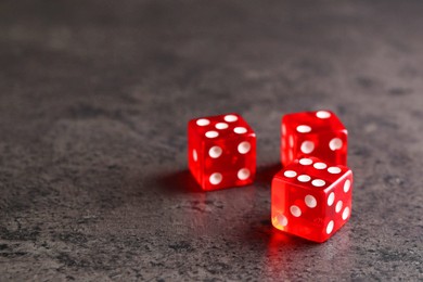 Three red game dices on grey textured table