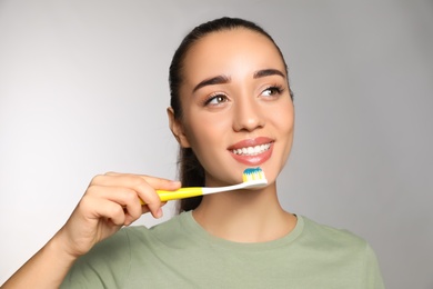 Photo of Woman holding toothbrush with paste on light background