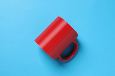 Photo of One red ceramic mug on light blue background, top view
