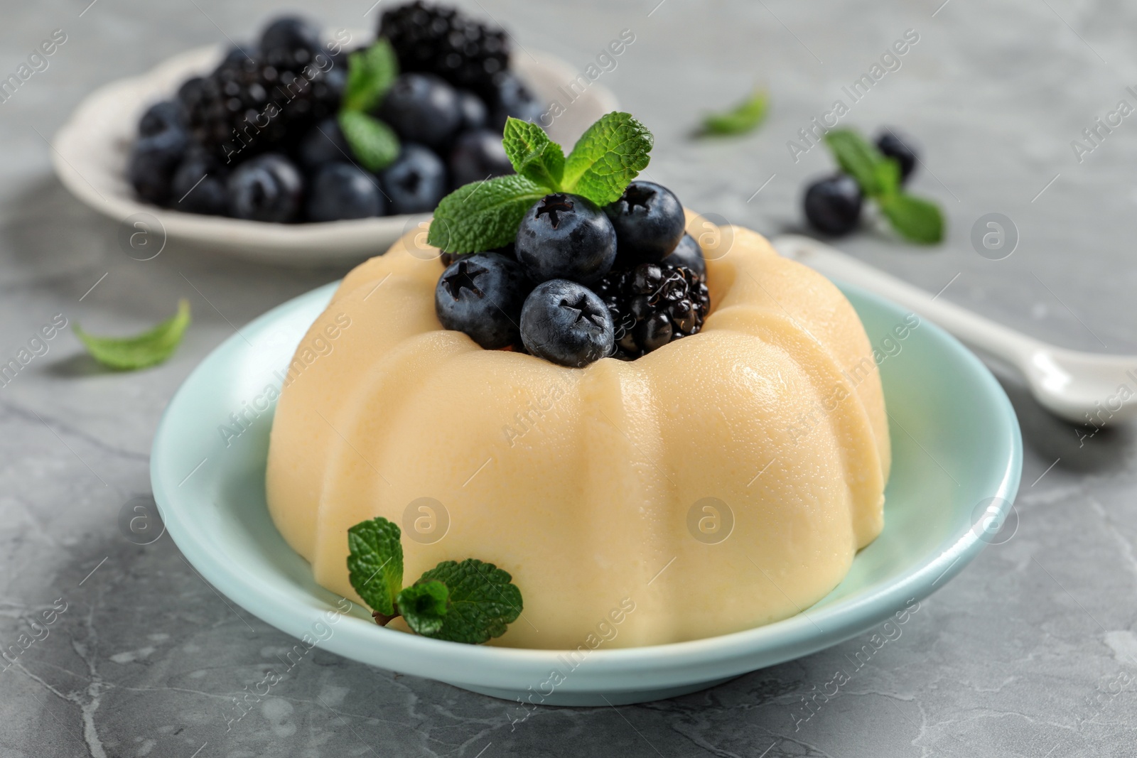 Photo of Delicious semolina pudding with berries on light grey table