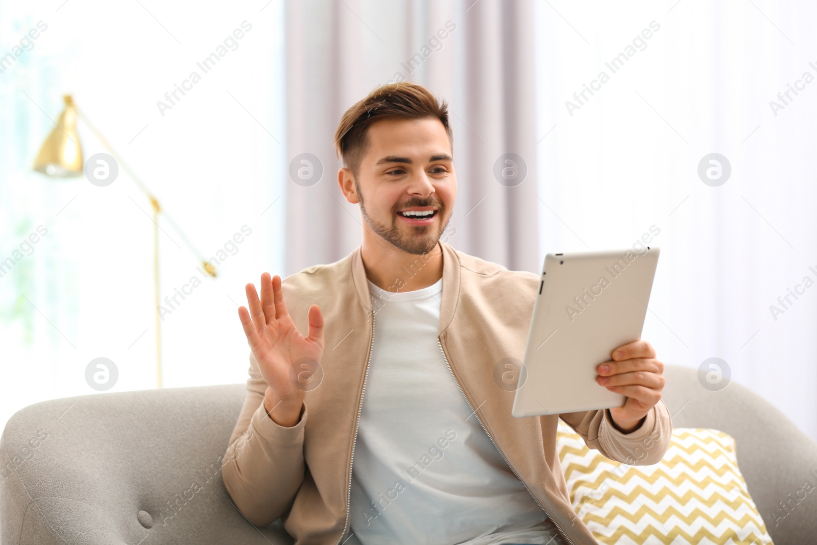 Photo of Man using tablet for video chat in living room