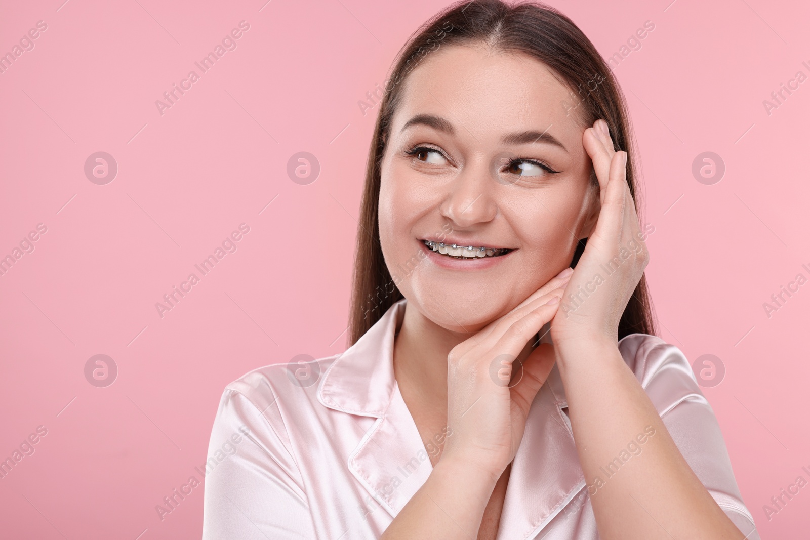 Photo of Smiling woman with dental braces on pink background. Space for text